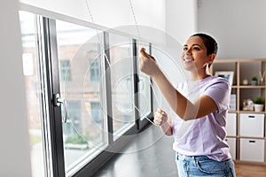 Woman opening window roller blinds