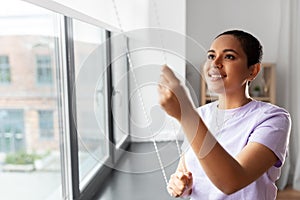 Woman opening window roller blinds