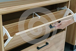 Woman opening wooden shoes storage cabinet for keep her shoes