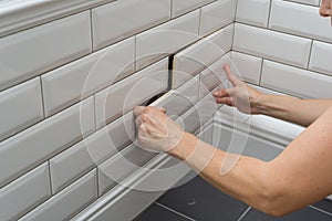 Woman opens, closes the hidden revision sanitary hatch on the wall of tile under the bathroom.