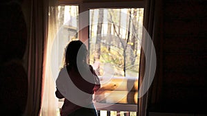 Woman Opens curtains and the Door to the Balcony Overlooking the Forest on sunny autumn day. slow motion. 3840x2160