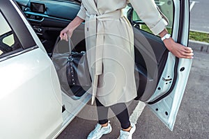 Woman opens door of business class taxi car, bag in her hand after shopping, fashionable modern fashion girl, car