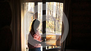 Woman Opens a Door to the Balcony Overlooking the Forest on sunny autumn day