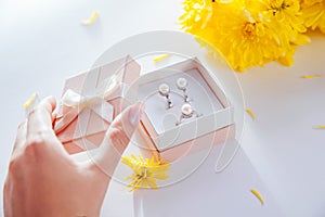 Woman opens a gift box with a set of pearl jewellery surrounded with flowers