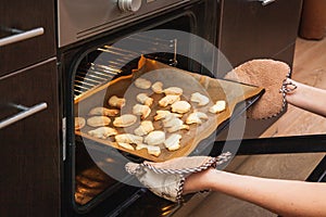 Woman opens the oven where cookies are baked for Halloween. Woman opens the oven where cookies are baked for Halloween