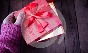 A woman opens a red gift and there is a bright light