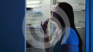 Woman opens refrigerator and looks at tempting donuts