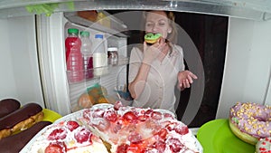 Woman opens the refrigerator at night. night hunger. diet gluttony