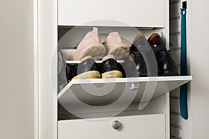 Woman opens Shoe Cabinet with Footwear in hallway. Storage ideas. Seasonal shoes storage