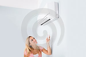 Woman Operating Air Conditioner With Remote