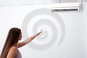 Woman operating air conditioner with remote control