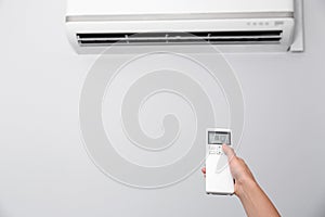 Woman operating air conditioner with remote control