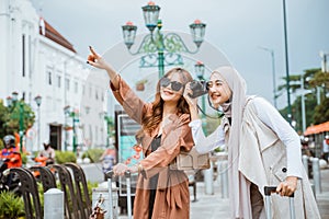 woman operating her camera beside the woman with long brown hair