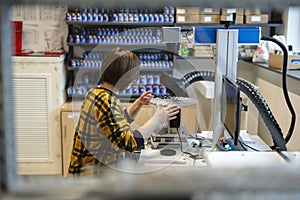 Woman operating a machine that prints logos on pens