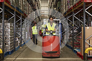 Woman operating tow tractor in a busy distribution warehouse