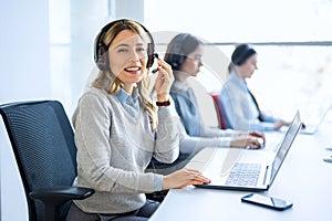 Woman operator agent with headsets and her team working in a call center customer service office.