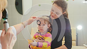 Woman optometrist in clinic checks eyesight at little girl - child`s ophthalmology