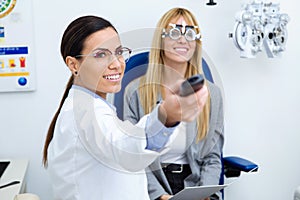 Woman optometrist with trial frame checking patient`s vision at eye clinic. Selective focus on doctor.