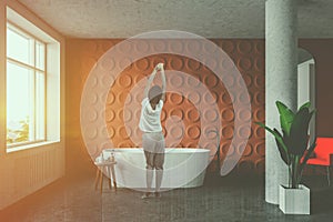 Woman in orange bathroom with tub