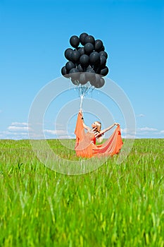 Woman in orange dress with black balloons