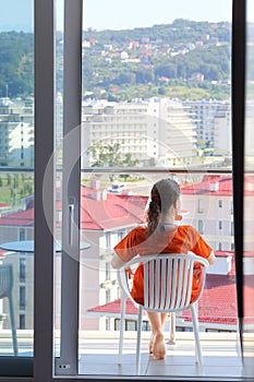 Woman in an orange dress sitting on terrace in