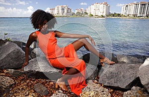 Woman in orange posing on the rocks