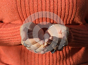 Woman in Orange Sweater with Cupped Hands