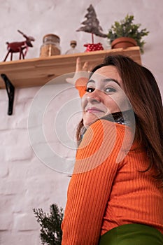 A woman in an orange sweater decorates the house for the new year, Christmas balls and toys, decorating the kitchen