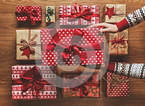 Woman organising beautifully wrapped vintage christmas presents on wooden background, image with haze