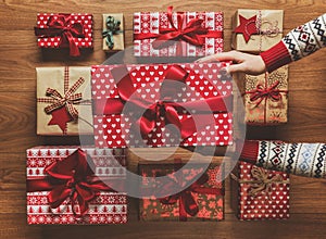 Woman organising beautifully wrapped vintage christmas presents on wooden background, image with haze photo