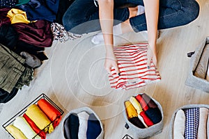 Woman folding pile of clothes on the floor, organizing stuff photo