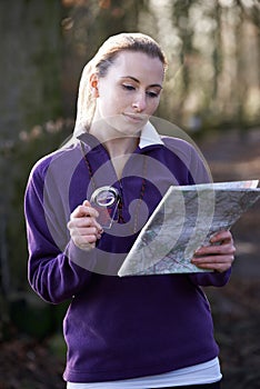 Woman Orienteering In Woodlands With Map And Compass photo