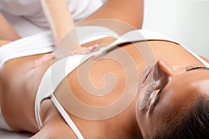 Woman at osteopathic massage with therapist hand on stomach.
