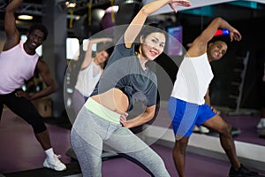 Woman with others doing step aerobics in fitness club