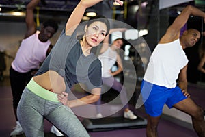 Woman with others doing step aerobics in fitness club