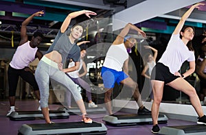 Woman with others doing step aerobics in fitness club