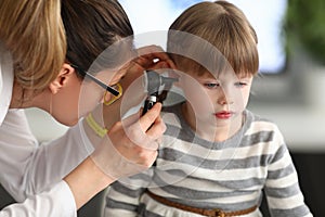 Woman otorhinolaryngologist examines little girl`s ear with otoscope in clinic