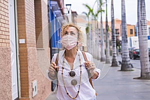 Woman outdoor in the city in leisure activity walking and enjoying wearing a pink protection coronavirus mask - covid-19 and