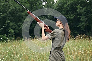 Woman on outdoor Holds the gun up aiming hunting green overalls