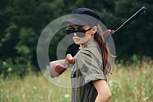 Woman on outdoor Hunting shotgun sunglasses green jumpsuit black cap green trees