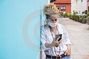 Woman outdoor in the street useing modern phone and wearing protection mask -. coronavirus and covid-19 related new normality