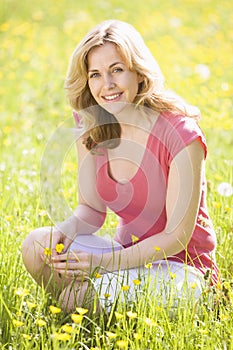 Woman outdoors holding flower smiling