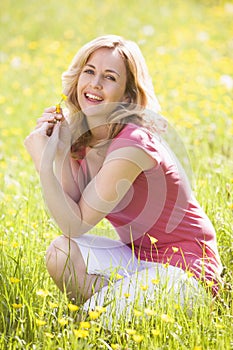 Woman outdoors holding flower smiling