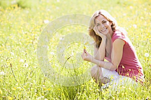 Woman outdoors holding flower smiling