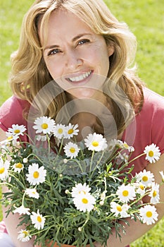 Woman outdoors holding flowers smiling