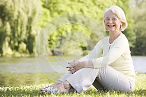 Woman outdoors at park by lake smiling