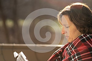 Woman outside in early morning with sunflare reading a book.