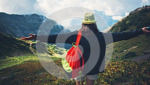 Woman with outspread hands standing among beautiful mountain meadows