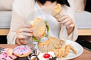 woman over eating fast food burgers, fired chicken, donuts, and desserts,  Binge Eating Disorder BED concept