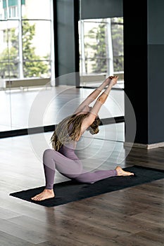 A woman in overalls is engaged in yoga in the hall.
